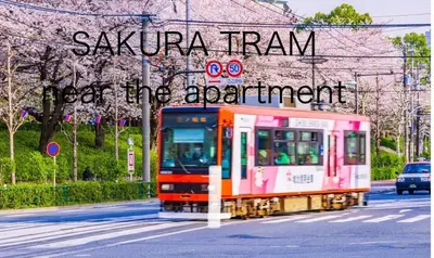a train traveling down a street under a sign at Home Tokyo Takinogawa in Tokyo