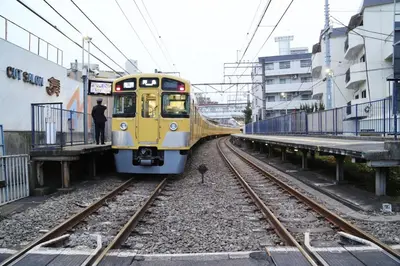 a yellow train is coming down the tracks at Pr22 \u4e0b\u843d\u5408 in Tokyo