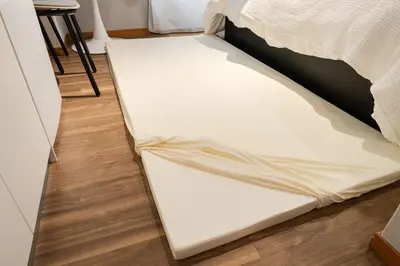 a bed frame with a sheet on the floor at 7minute walk from JR Takadanobaba Station, 11 minutes from Shinjuku ,Wi-Fi, simple and high-quality space in Tokyo