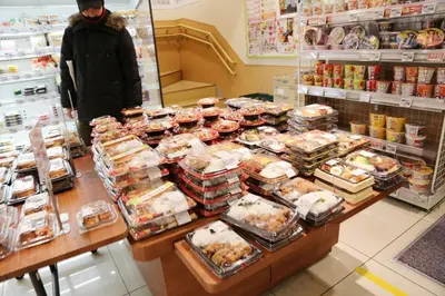 a woman standing in a grocery store with a counter full of food at Pr33\u4e0b\u843d\u5408 in Tokyo