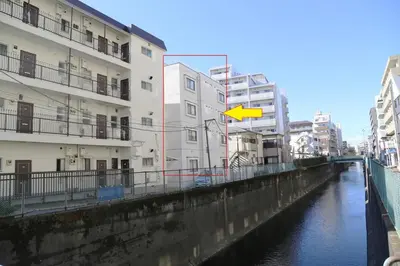 a yellow arrow on a building next to a river at Pr33\u4e0b\u843d\u5408 in Tokyo