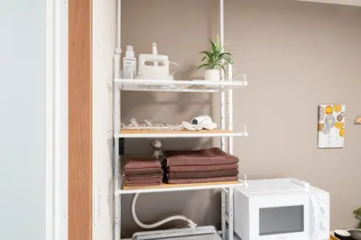 a shelf with towels and a microwave in a room at Parkside Shinjuku Tokyo in Tokyo