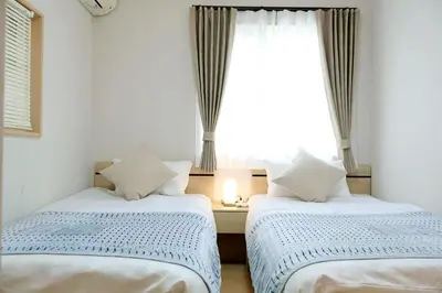 two beds in a room with a window at \u4e0a\u91ce \u79cb\u8449\u539f \u30a8\u30ea\u30a2 5LDK \u30c8\u30a4\u30ec3\u7b87\u6240 \u6d74\u5ba42\u7b87\u6240 \u30ad\u30c3\u30c1\u30f3 \u30c6\u30e9\u30b9\u3042\u308a\u8cb8\u5207\u4e00\u8ed2\u5bb6a in Tokyo