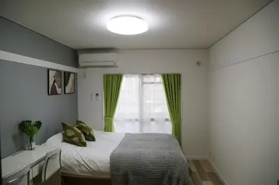 a bedroom with a bed with green curtains and a window at Pr42\u4e0b\u843d\u5408 in Tokyo