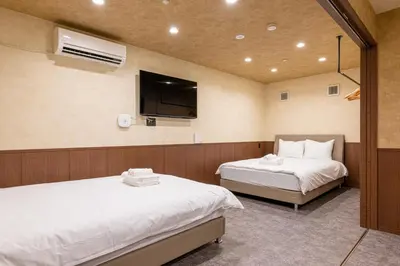 a room with two beds and a flat screen tv at SEEK Tokyo in Wada