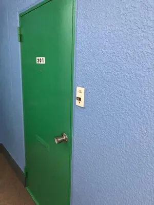 a green door with the number next to a blue wall at \u685c\u5c4bSakuraya201 in Tokyo