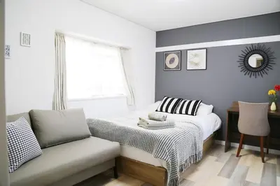 a bedroom with a bed and a couch and a window at Pr46 \u4e0b\u843d\u5408 in Tokyo
