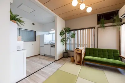 a living room with a green couch and a kitchen at \u4e0a\u6c60\u888b\u6238\u5efa\u3066 in Tokyo