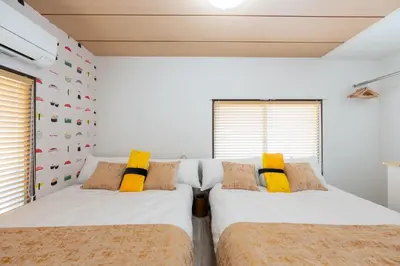 two beds in a bedroom with white walls and yellow pillows at \u4e0a\u6c60\u888b\u6238\u5efa\u3066 in Tokyo