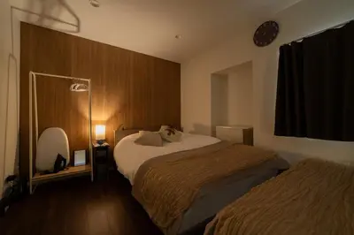 a bedroom with two beds and a clock on the wall at \u30a2\u30f3\u30c9\u30b9\u30c6\u30a4\u5927\u5cf63\u4e01\u76ee in Tokyo