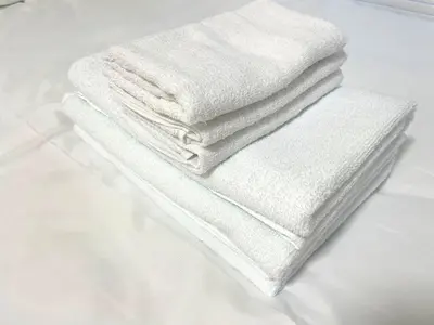 a stack of white towels sitting on a bed at Gest house Near Disneyland in Edogawa
