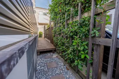 a wooden walkway with a ivy covered wall at shinjuku premier suites tokyo in Tokyo