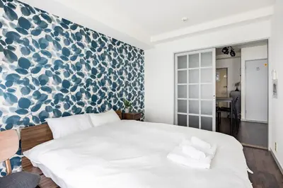 a bedroom with a white bed and a blue and white wall at BAi\u304a\u82b1\u8336\u5c4b1\u4e01\u76ee\u30d1\u30fc\u30eb\u30cf\u30a4\u30c4202 in Tokyo