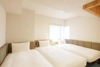 two beds in a white room with a window at HOTEL AMANEK Asakusa Sakurabashi in Tokyo