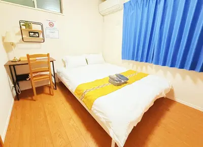 a room with a bed and a desk with a blue curtain at \u6c60\u888b\u672c\u753a202 in Tokyo