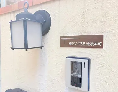 a light on the side of a building with a sign at \u6c60\u888b\u672c\u753a202 in Tokyo