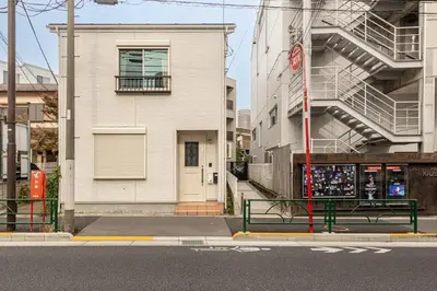 an empty street with a building and two green benches at \u6771\u4e2d\u91ce in Tokyo