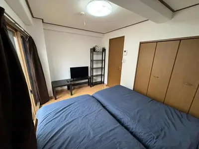 a bedroom with a blue bed and a television at Tokyo Stay Ikebukuro #303 in Tokyo