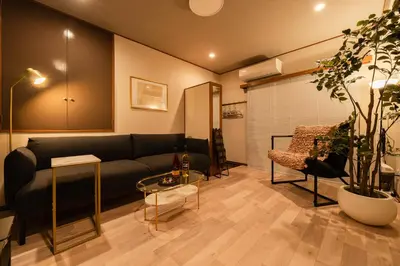 a living room with a black couch and a chair at #32 -\u670d\u90e8\u30d3\u30eb\u6771\u6c60\u888b- Condo in Tokyo