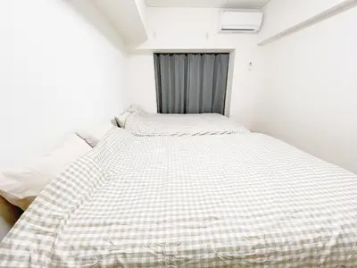 a bed with a checkered blanket in a room at Ikebukuro home 18 in Tokyo