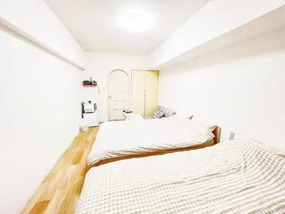 two beds in a bedroom with white walls and wood floors at Ikebukuro home 18 in Tokyo