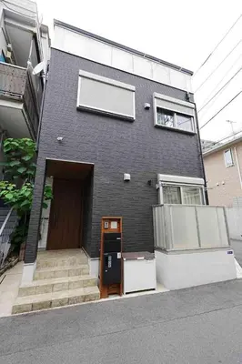 a black house with a door and stairs in front of it at 100 INN Suite in Tokyo