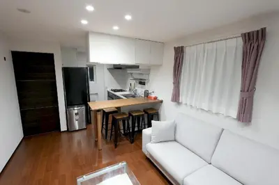 a living room with a white couch and a kitchen at 100 INN Suite in Tokyo