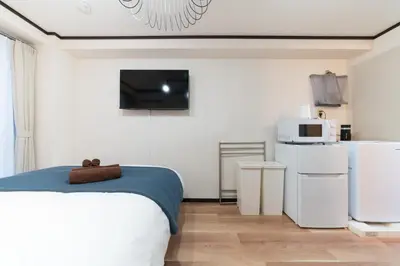 a bedroom with a bed and a microwave and a refrigerator at Nishi Shinjuku City House \u897f\u65b0\u5bbf\u30b7\u30c6\u30a3\u30fc\u30cf\u30a6\u30b9 - \u6771\u4eac\u89b3\u5149\u306b\u4fbf\u5229\u306a\u65b0\u5bbf\u30b9\u30c6\u30a4 in Tokyo