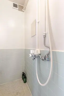 a shower in a bathroom with blue tiles at tkm\u5317\u5c0f\u5ca91\u4e01\u76ee101 in Tokyo