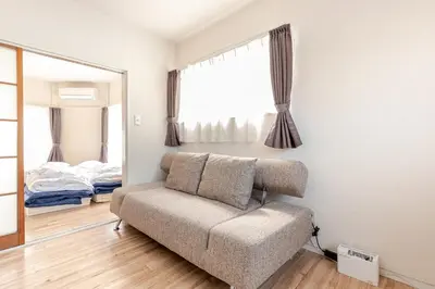 a living room with a couch and a mirror at tkm\u5317\u5c0f\u5ca91\u4e01\u76ee101 in Tokyo