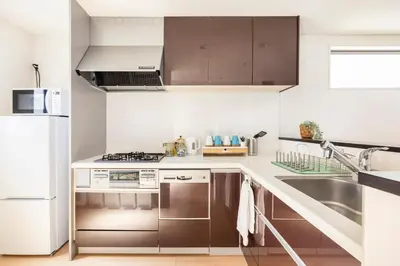 a kitchen with stainless steel appliances and brown cabinets at Cozy Stay Kanamecho in Tokyo