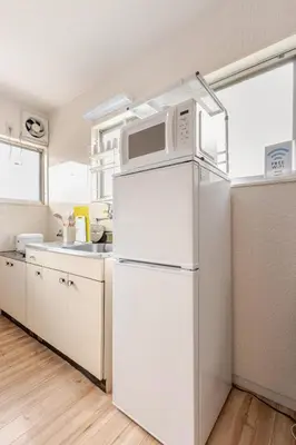 a kitchen with a white refrigerator and a microwave at tkm\u5317\u5c0f\u5ca91\u4e01\u76ee103 in Tokyo