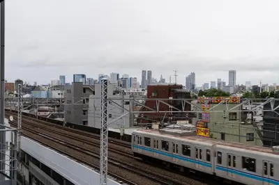 a train on tracks with a city in the background at Apartment hotel 3 minutes walk from JR Asagaya station Ideal base for exploring Tokyo HOTEL CtrlD ASAGAYA in Tokyo