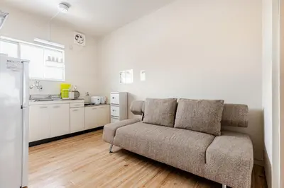 a living room with a couch and a kitchen at tkm\u5317\u5c0f\u5ca91\u4e01\u76ee202 in Tokyo