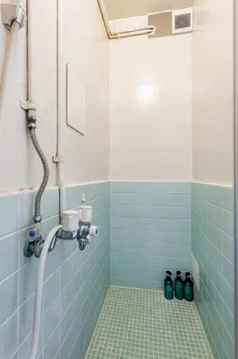 a bathroom with a shower with blue tiles at tkm\u5317\u5c0f\u5ca91\u4e01\u76ee202 in Tokyo