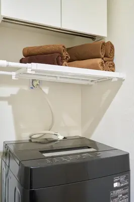 a shelf above a washing machine with towels at N 5min to waseda sta designer condo high security free wifi in Tokyo