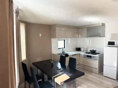 a kitchen with a black table and chairs and a refrigerator at Beauty House in Tokyo