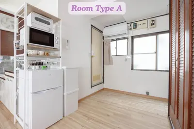 a kitchen with a white refrigerator and a tv at Sakura Hotel Koiwa in Tokyo