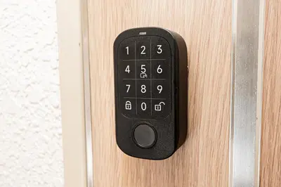 a black remote control on a wooden door at 2 min walking distance to station cozy room in central tokyo in Tokyo