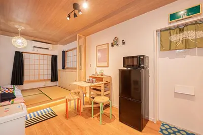 a living room with a refrigerator and a table at 2 min walking distance to station cozy room in central tokyo in Tokyo