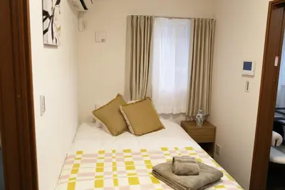 a small bedroom with a bed with a checkered blanket at Km102\u4e0a\u6c60\u888b in Tokyo