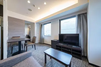a living room with a couch and a television and a table at APA SERVICED RESIDENCE SHINJUKU by unito in Tokyo