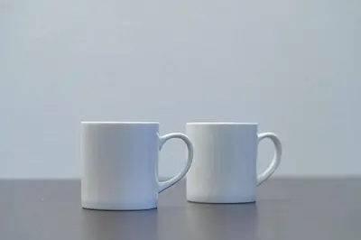 two white coffee mugs sitting next to each other at APA SERVICED RESIDENCE SHINJUKU by unito in Tokyo