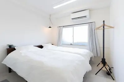 two beds in a white bedroom with a window at T4U Shinjyuku in Tokyo