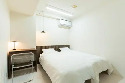 a bedroom with a white bed and a night stand at T4U Shinjyuku in Tokyo