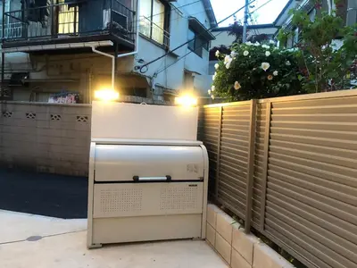 a refrigerator sitting on a sidewalk next to a fence at 201\u53f7 \u5c71\u624b\u7ebf\u8fd1\u4e0a\u91ce\u4e00\u7ad9\u590d\u5f0f\u6e29\u99a8\u65b0\u516c\u5bd3 in Tokyo
