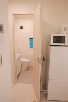 a white bathroom with a microwave and a refrigerator at Room #301 - Cozy Stay Higashi Ikebukuro in Tokyo
