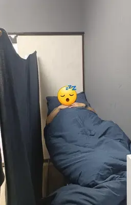 a person laying on a bed with a smiley face at Y's House Okubo in Tokyo