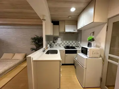 a kitchen with white appliances and a couch at 302\u6d89\u8c37\u533a\u57df \u4e58\u7535\u8f664\u5206\u949f\u5230\u8fbe\u65b0\u5bbf \u5df4\u58eb\u76f4\u8fbe\u6d89\u8c37\u6b65\u884c\u5230\u897f\u65b0\u5bbf\u4e94\u4e01\u76ee8\u5206\u949f max5 in Tokyo