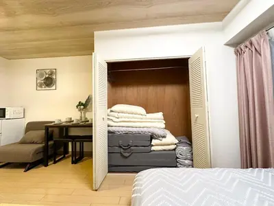 a room with a bed and a desk and a table with towels at 302\u6d89\u8c37\u533a\u57df \u4e58\u7535\u8f664\u5206\u949f\u5230\u8fbe\u65b0\u5bbf \u5df4\u58eb\u76f4\u8fbe\u6d89\u8c37\u6b65\u884c\u5230\u897f\u65b0\u5bbf\u4e94\u4e01\u76ee8\u5206\u949f max5 in Tokyo